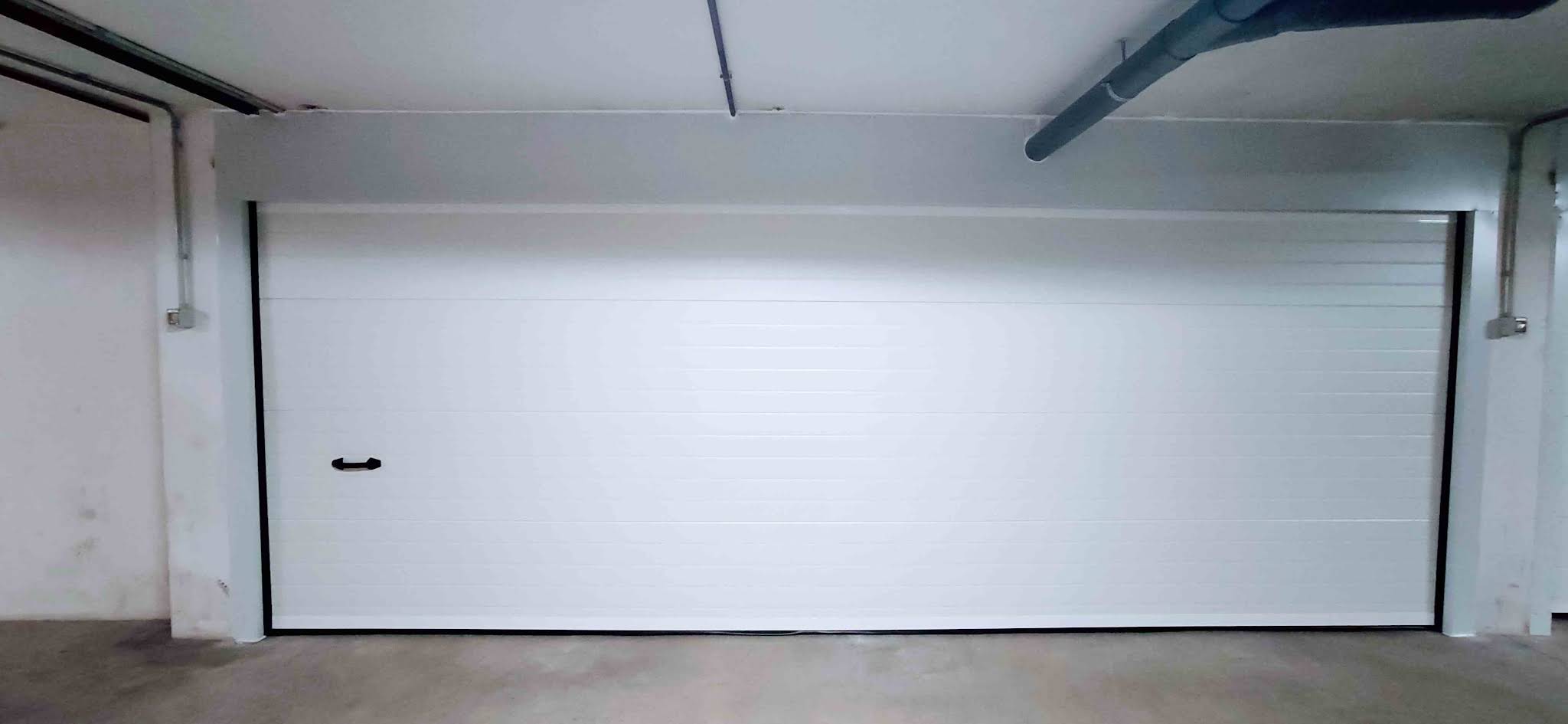 Puerta seccional blanca de gran tamaño en garaje comunitario