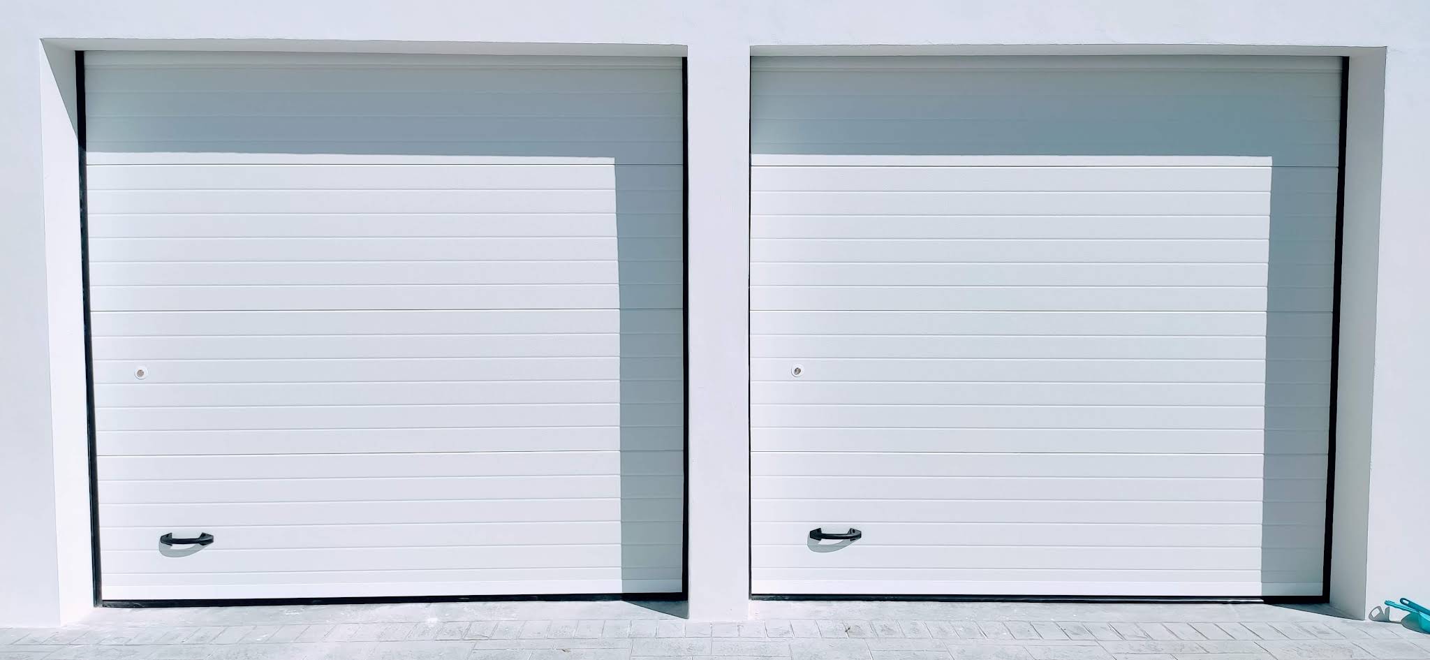 Doble puerta seccional blanca instalada en fachada