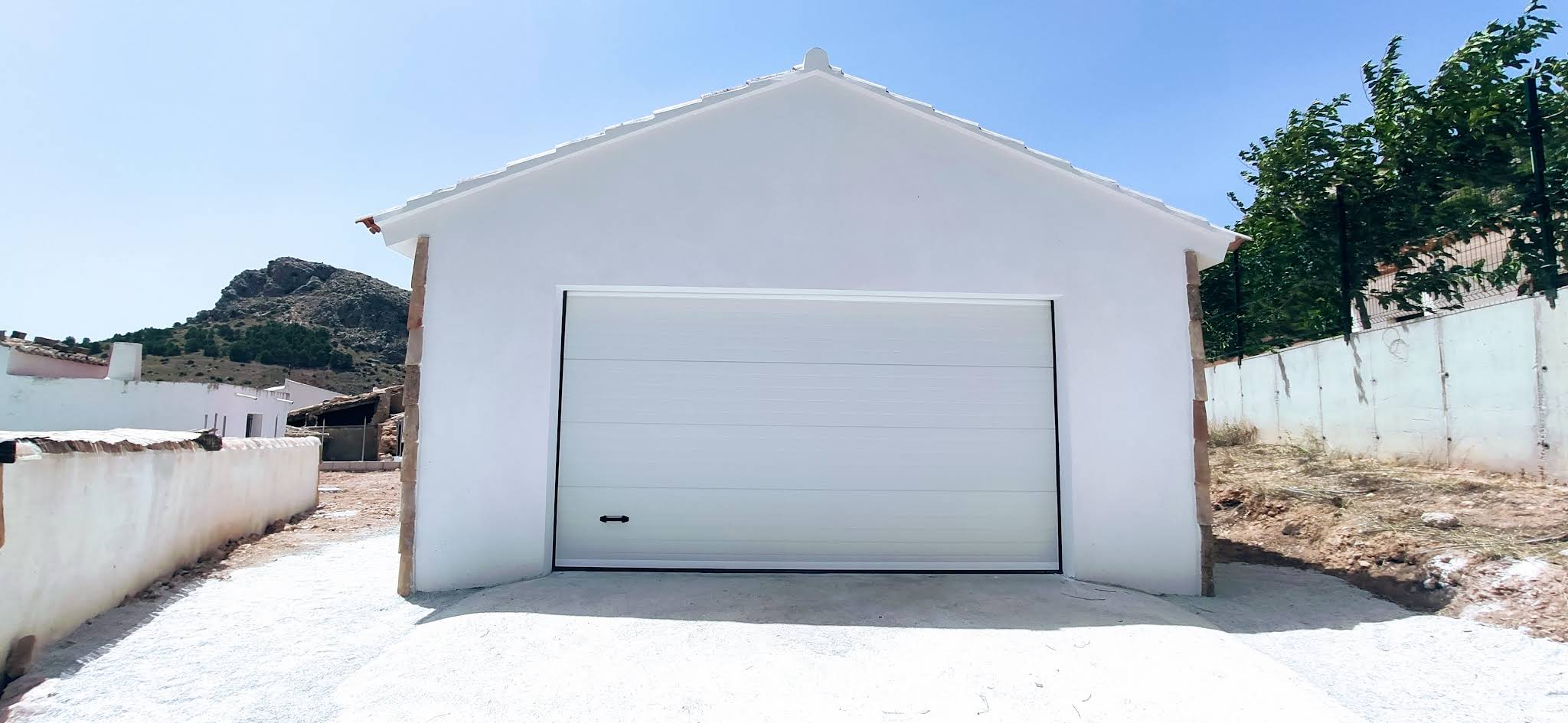 Puerta seccional blanca en garaje rural de obra nueva